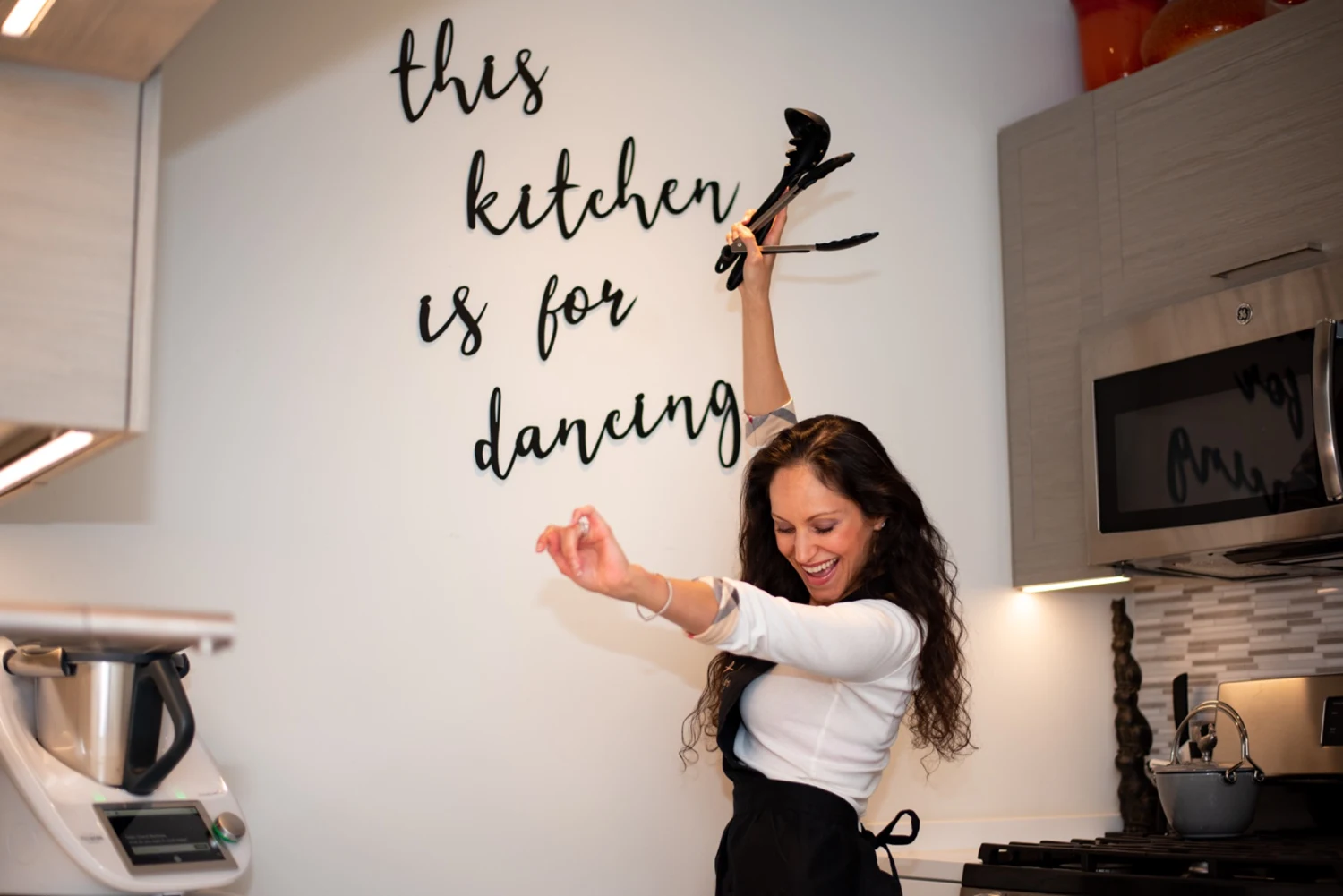 Cheryl dancing with cooking utensils in her kitchen